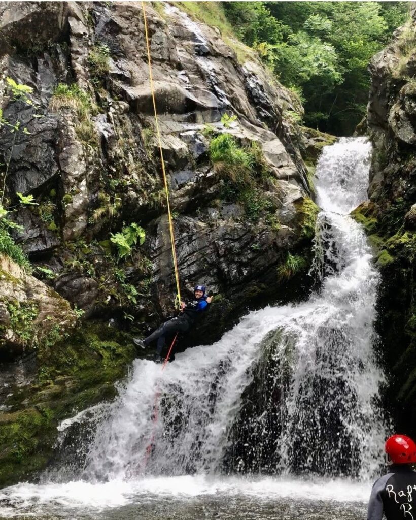 Hombre rapelando por una cascada